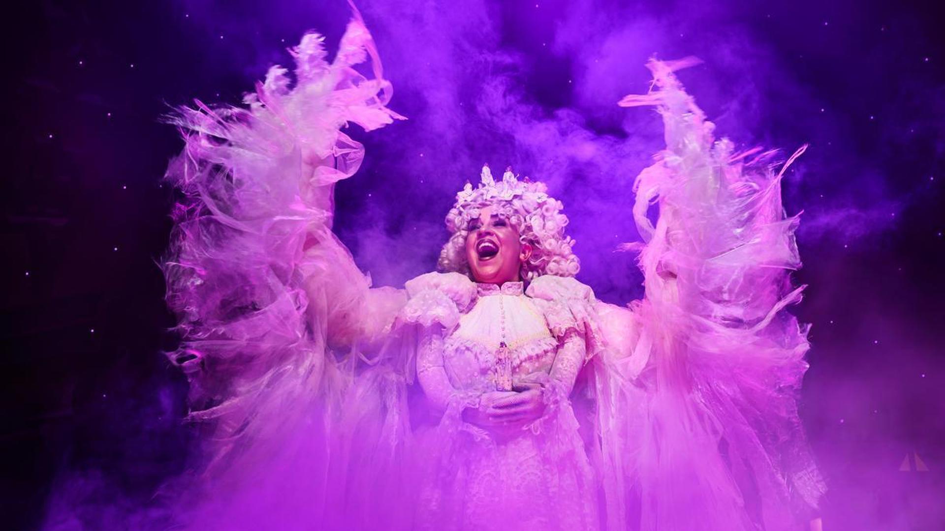 A performer stands on stage dressed as an angel.