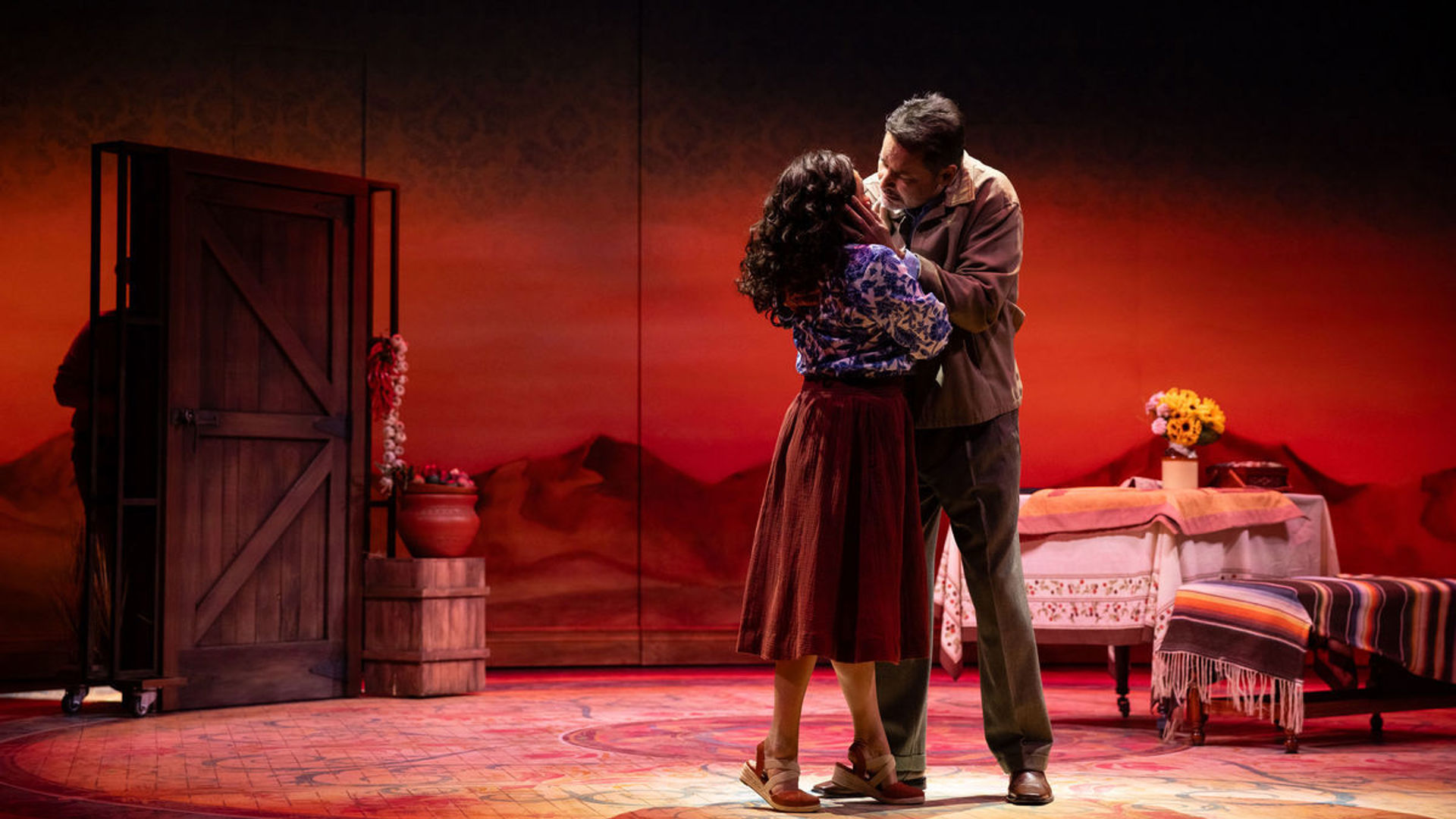 Two actors lean in to kiss each other.