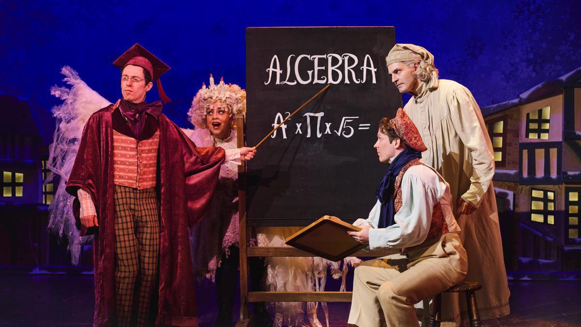 Four performers gather on stage around a chalkboard that says "Algebra" on it, with an equation below it.