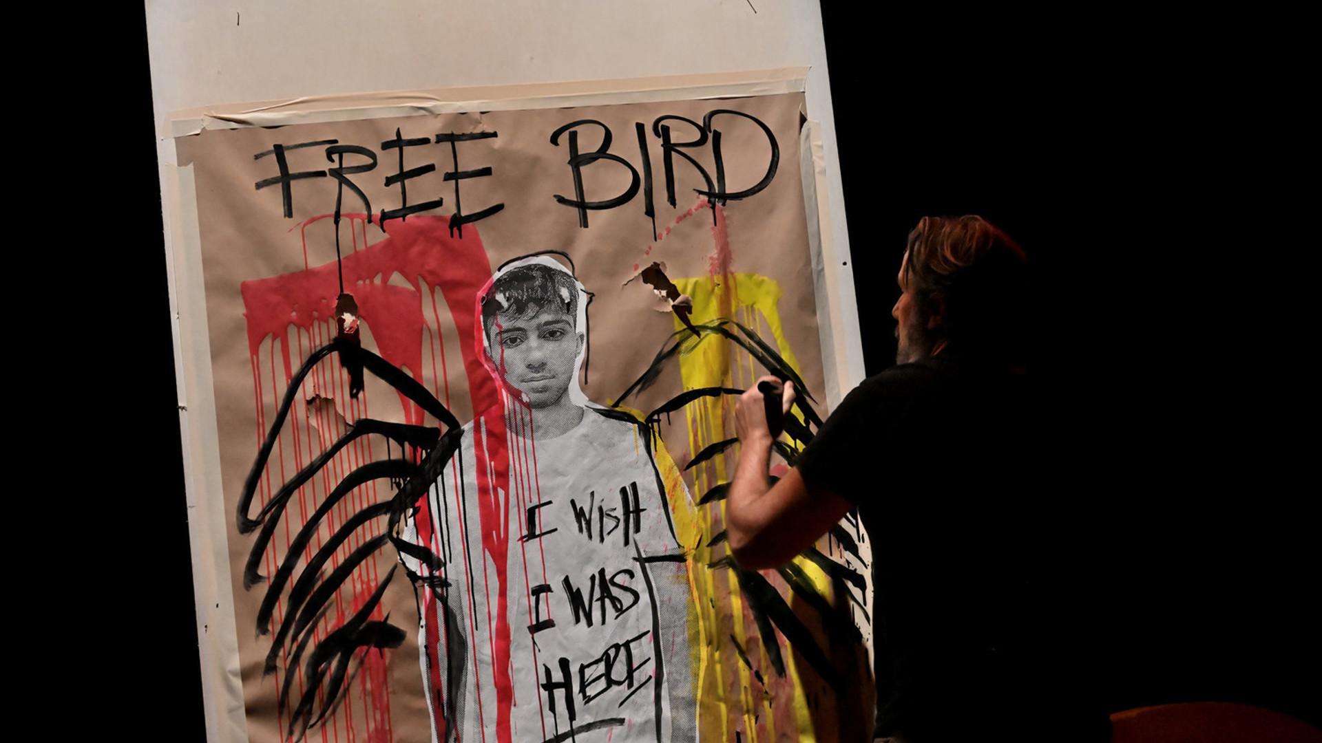 Manuel Oliver paints wings on the portraight of his son. "I wish I was Here" is written on his son's shirt.